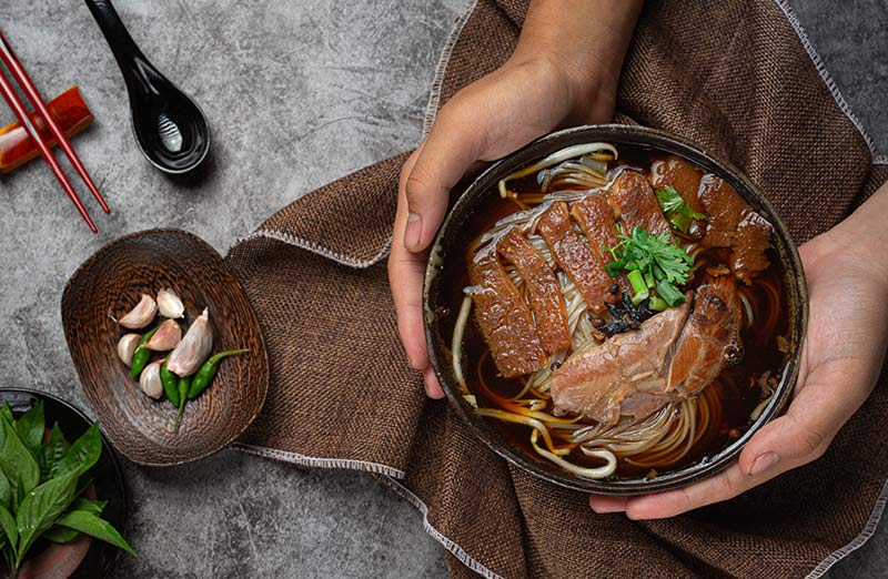 Bol asiático de carne con fideos. En la imagen aparecen ajos y pimientos.