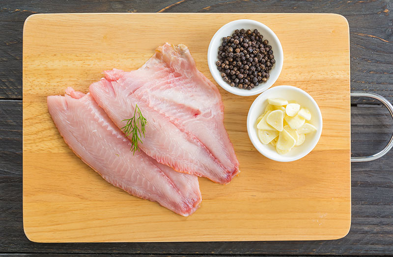 Pescado blanco limpio, encima de una tabla de madera.