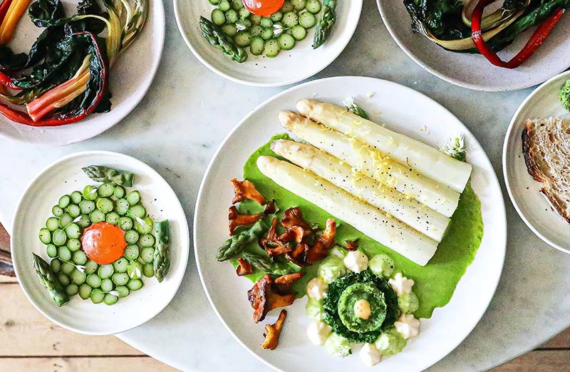 Platos de verduras con salsa, espárragos blancos, espárragos verdes y setas.