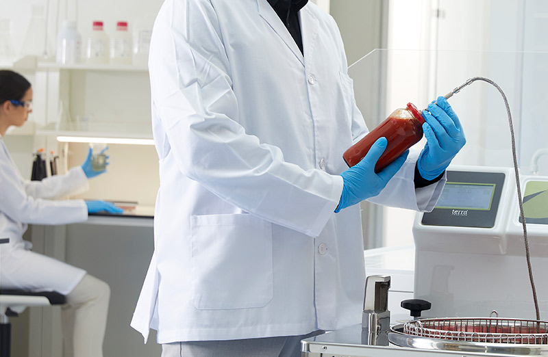 A technician inspecting a tomato container with the core probe of the autoclave to showcase the BRUCEFO facilities.